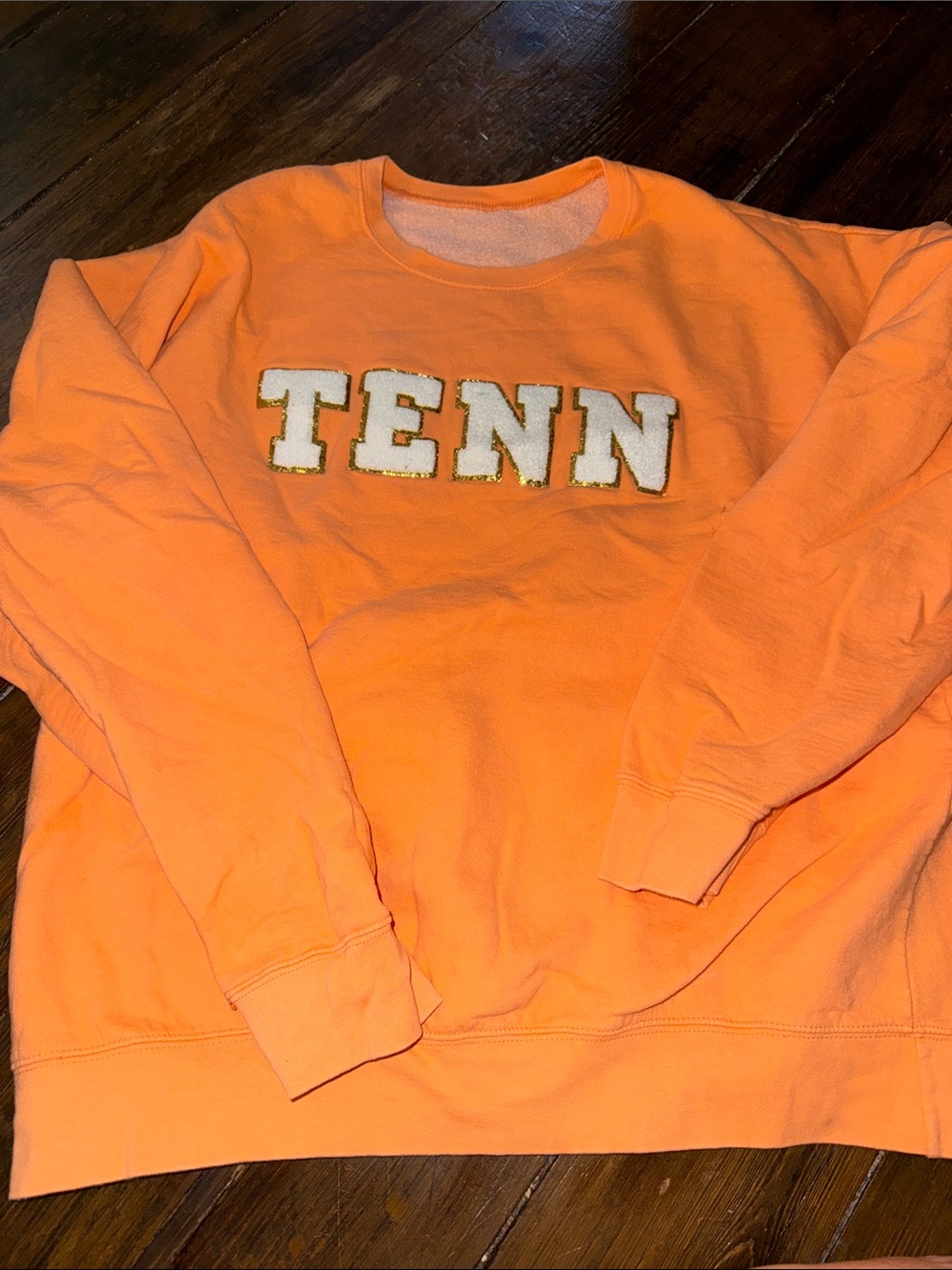 Orange crewneck sweatshirt with a classic collegiate style.